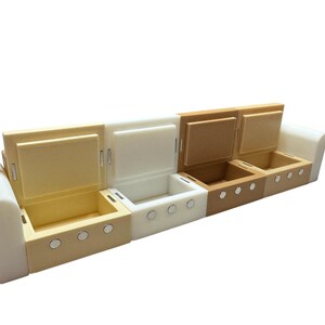 May include: A white, beige, and brown sofa with four compartments that open and close. Each compartment has a silver latch and a row of silver buttons.