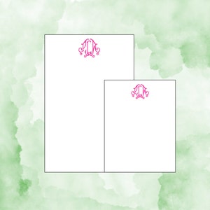 May include: Two blank white stationery note cards with a pink monogram of the letters "LCW" in a decorative script font.