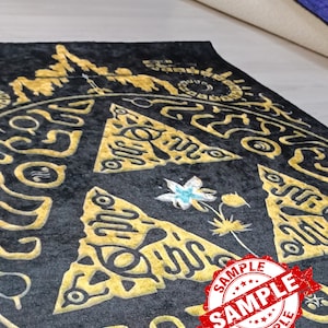 May include: A black and gold rug with a triangular pattern and a flower design. The rug has a "SAMPLE" stamp on it.