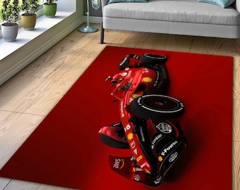May include: Red race car rug with a black tire and the words "aws", "Santoni", and "V-Power" on the side. The rug is on a wooden floor.