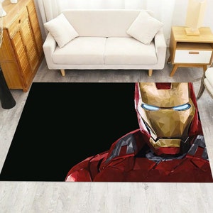 Könnte beinhalten: Rechteckiger Teppich mit einer Low-Poly-Illustration von Iron Mans Gesicht und Oberkörper in Rot, Gold und Grau vor schwarzem Hintergrund. Der Teppich liegt auf einem hellen Holzboden.