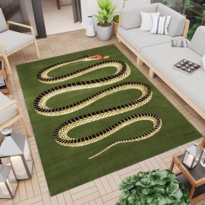 May include: A green rug featuring a black and gold snake design. The snake is curled up in a circle and has a red apple in its mouth. The rug has a green background and is made of a soft, plush material.
