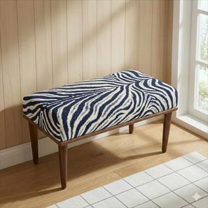May include: A rectangular bench with a zebra print seat in navy blue and white. The bench has a dark brown wooden frame and legs. The bench is placed on a light wood floor.