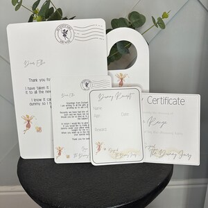 May include: A set of white stationery items featuring fairy illustrations and text. The collection includes a letter, a door hanger, and cards. The text includes phrases like "Dummy Fairy" and "Air Mail", with delicate floral designs.