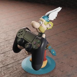 May include: A black and green video game controller held by a cartoon figure of a man with a winged helmet. The figure is standing on a blue and green base.
