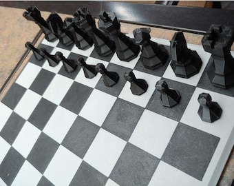 May include: A black and white chessboard with black chess pieces arranged in a row on the board. The pieces include a king, queen, rook, bishop, knight, and pawn.
