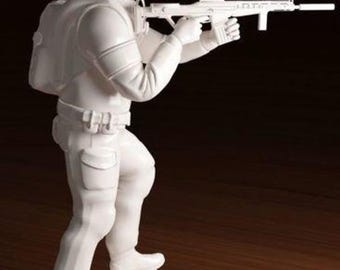 May include: White plastic figurine of a soldier holding a rifle. The soldier is wearing a helmet and a backpack. The figurine is standing on a white base.