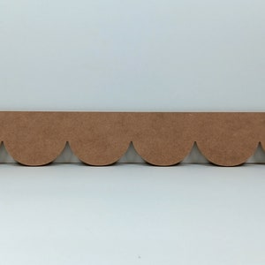 May include: A brown wooden scalloped trim with a decorative edge. The trim is about 12 inches long.