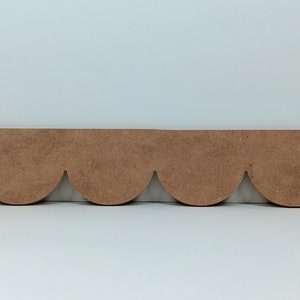 May include: A brown wooden scalloped trim with a decorative edge. The trim is made of unfinished wood and can be painted or stained to match any decor.