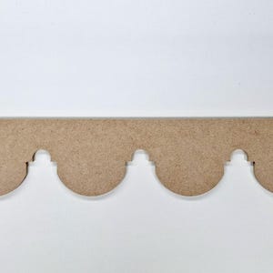 May include: A decorative wooden trim piece with a scalloped edge. The trim is a light brown color and has a repeating pattern of rounded arches. The piece is designed for use in home decor projects.
