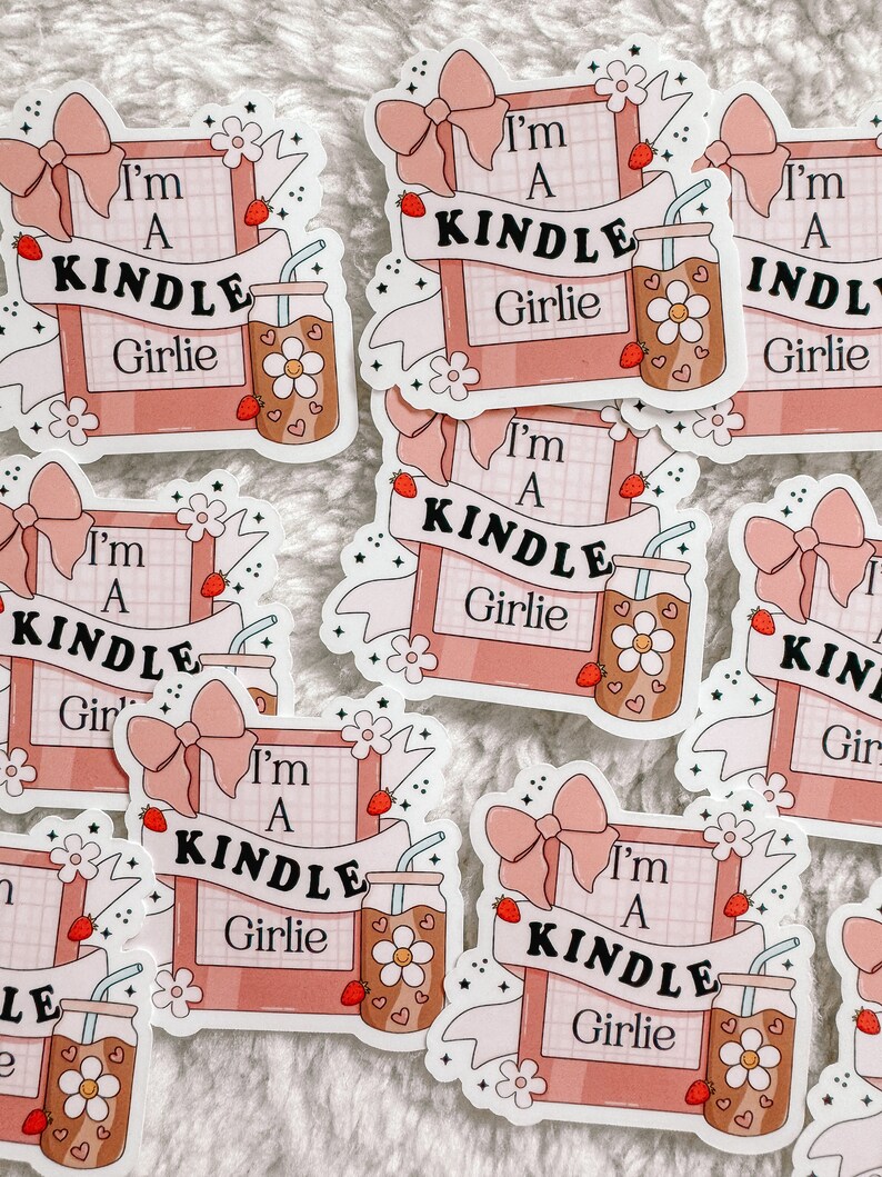 May include: A set of pink and white stickers with the text "I'm a Kindle Girlie" and a cartoon image of a drink with a straw and a flower. The stickers are decorated with pink bows, stars, and flowers.