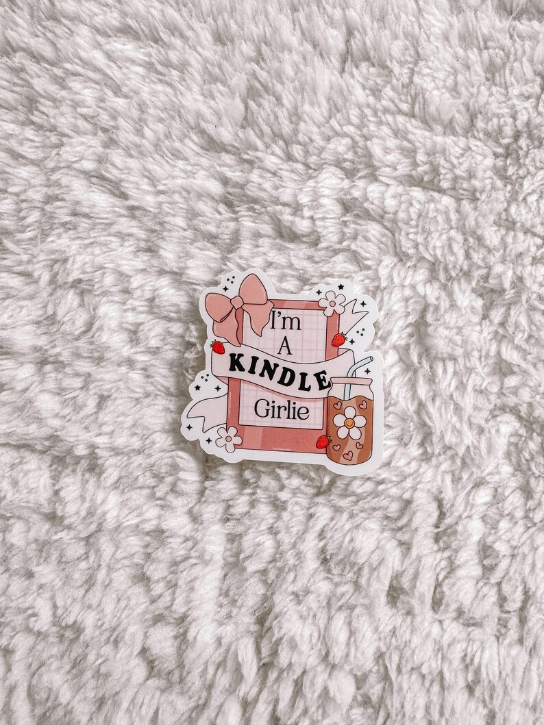 May include: A pink and white sticker with the text "I'm a Kindle Girlie" and a drawing of a book, a bow, a flower, and a glass of iced tea.