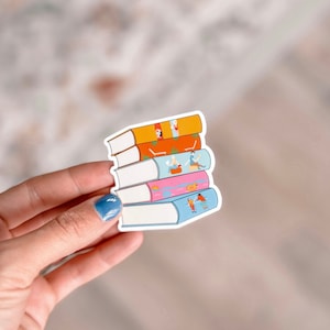 Puede incluir: Un conjunto de cinco pegatinas de libros coloridas con ilustraciones de personas y animales. Las pegatinas son blancas con un contorno negro y están dispuestas en una pila con la pegatina superior naranja, la siguiente naranja y roja, la siguiente naranja y azul, la siguiente rosa y azul, y la inferior blanca.