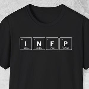 Puede incluir: Camiseta negra con las letras "INFP" en un estilo de tabla periódica. Las letras blancas están en cajas individuales. La camiseta está hecha de un material suave.