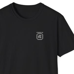 May include: A black t-shirt with a crew neck and short sleeves. The shirt has a small white square graphic on the upper chest with the text "OPTIMISED FOR AI" above and "AI" inside the square.