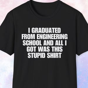 May include: Black t-shirt with white text: "I GRADUATED FROM ENGINEERING SCHOOL AND ALL I GOT WAS THIS STUPID SHIRT". The shirt has short sleeves and a crew neck.
