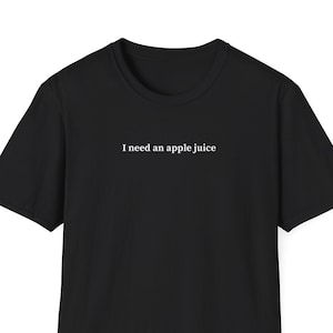 May include: Black t-shirt with the text "I need an apple juice" printed in white on the front.