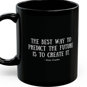 May include: Black ceramic coffee mug with a white quote that reads "The best way to predict the future is to create it." - Peter Drucker.