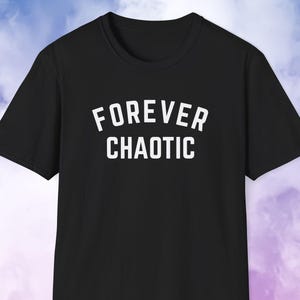 May include: Black t-shirt with the white text "FOREVER CHAOTIC" in a bold, sans-serif font. The shirt has short sleeves and a crew neck. The background is a gradient of blue, purple, and pink.