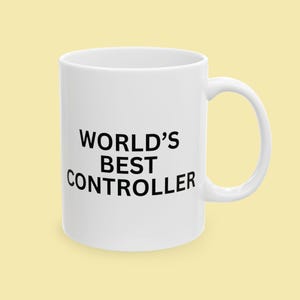 Puede incluir: Una taza de cerámica blanca con asa negra y el texto "But First, Coffee" en negrita negra. La taza se encuentra sobre un fondo borroso, sugiriendo un ambiente acogedor.