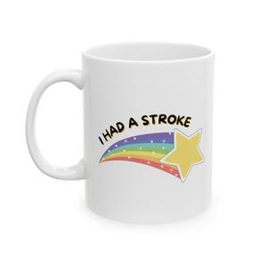 May include: White ceramic coffee mug with a black and white graphic of a rainbow shooting star with the text "I had a stroke".
