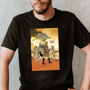 Peut inclure: Un t-shirt noir avec un imprimé graphique d'un personnage de Star Wars brandissant un sabre laser, avec d'autres personnages en arrière-plan.