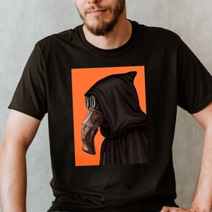 May include: Black t-shirt featuring a graphic of a plague doctor with a black hood and mask, set against an orange background. The plague doctor illustration is detailed with brown and silver accents. The t-shirt is a classic crew neck style.