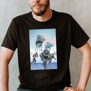 Op de afbeelding: Een zwart T-shirt met een grafische print van een Star Wars-scène. De scène toont een groep soldaten die naar een grote, witte AT-AT-walker rennen. De achtergrond is een besneeuwd landschap.