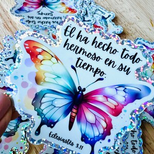 May include: A colorful butterfly sticker with glitter accents. The sticker features the text "El ha hecho todo hermoso en su tiempo" and the Bible verse "Ecclesiastes 3:11".