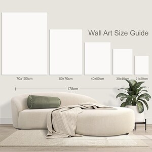 May include: A wall art size guide displays five blank rectangular canvases with dimensions in centimeters. A beige sofa with a green bolster pillow and a blanket is in front of the canvases. The text "Wall Art Size Guide" is above the canvases.