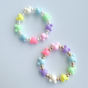 May include: Two colorful bracelets with pastel-colored Mickey Mouse head beads and gold beads.