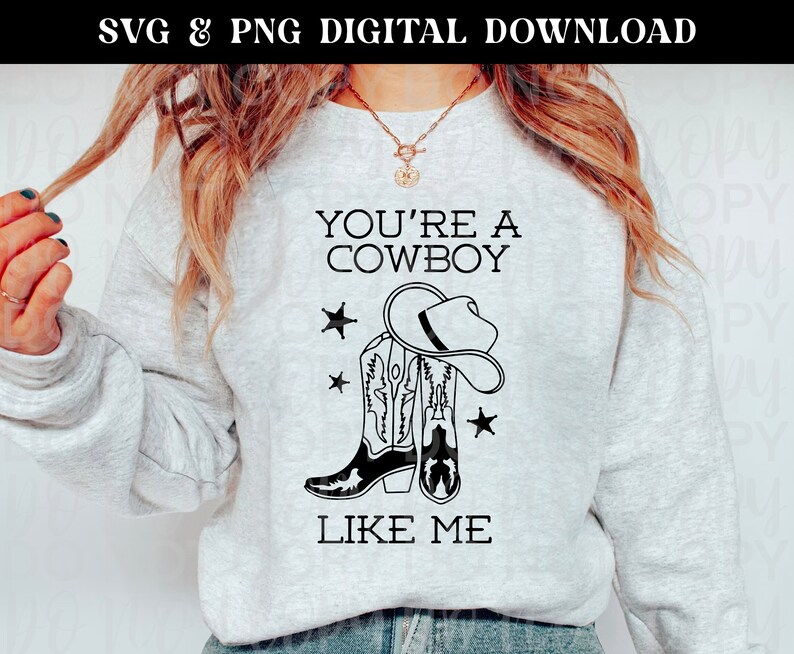 May include: A gray sweatshirt with the text "You're a Cowboy Like Me" in black. The design includes a pair of cowboy boots and a cowboy hat.