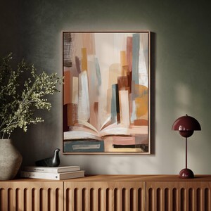 May include: Abstract art print in a wooden frame. The artwork features an open book at the bottom with colorful vertical shapes in shades of brown, beige, and blue. A modern, decorative piece for home decor.