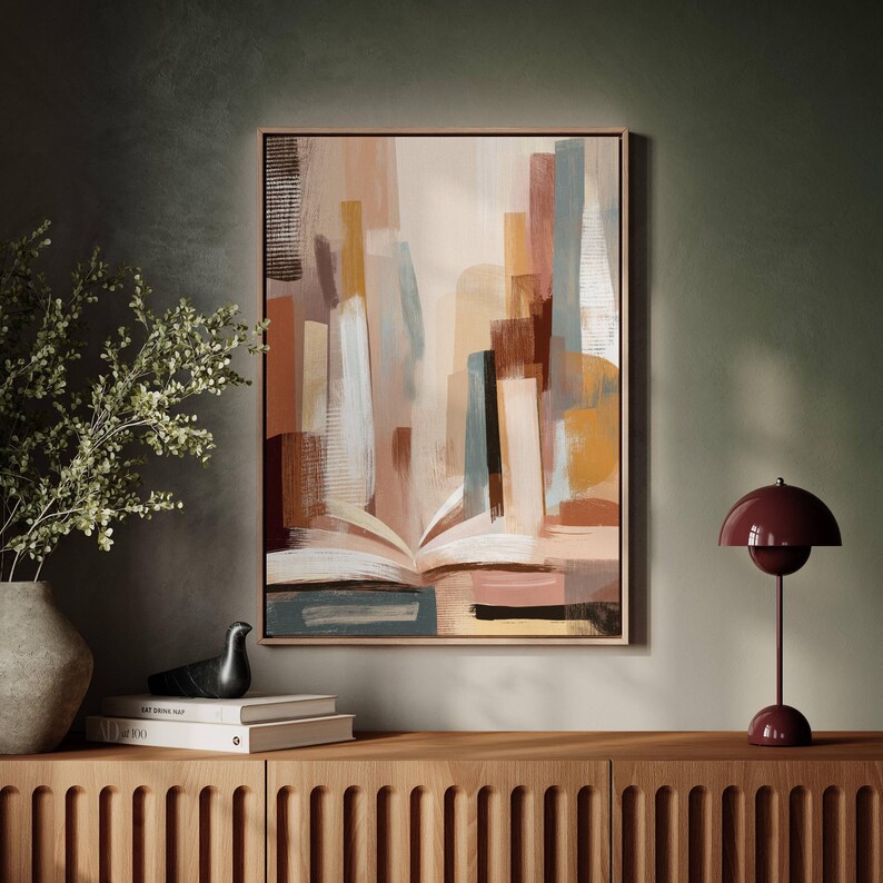 May include: Abstract art print in a wooden frame. The artwork features an open book at the bottom with colorful vertical shapes in shades of brown, beige, and blue. A modern, decorative piece for home decor.