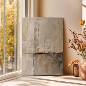 May include: Abstract art piece with a textured, neutral color palette. The artwork is displayed near a window with a view of fall foliage. A terracotta vase and a small glass bottle hold dried flowers, adding a touch of warmth to the scene.