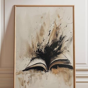 May include: Abstract art print featuring an open book with pages fanned out. The artwork uses a palette of beige, brown, and black, with dynamic brushstrokes and splatters emanating from the book's center. The print is framed in a light wood.