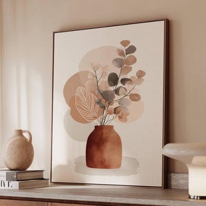 May include: A framed canvas art print featuring a terracotta vase with botanical elements in shades of brown, beige, and white. The artwork has a minimalist, abstract style with soft, rounded shapes and a neutral color palette, suitable for home decor.