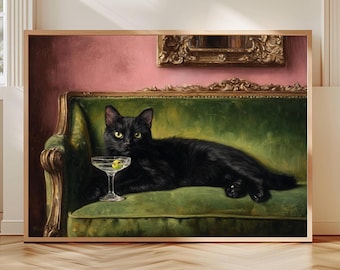 Op de afbeelding: Een ingelijste print met een zwarte kat die op een groene fluwelen bank ligt, met een martini glas met een olijf. De achtergrond toont een roze muur en een gouden decoratief frame.