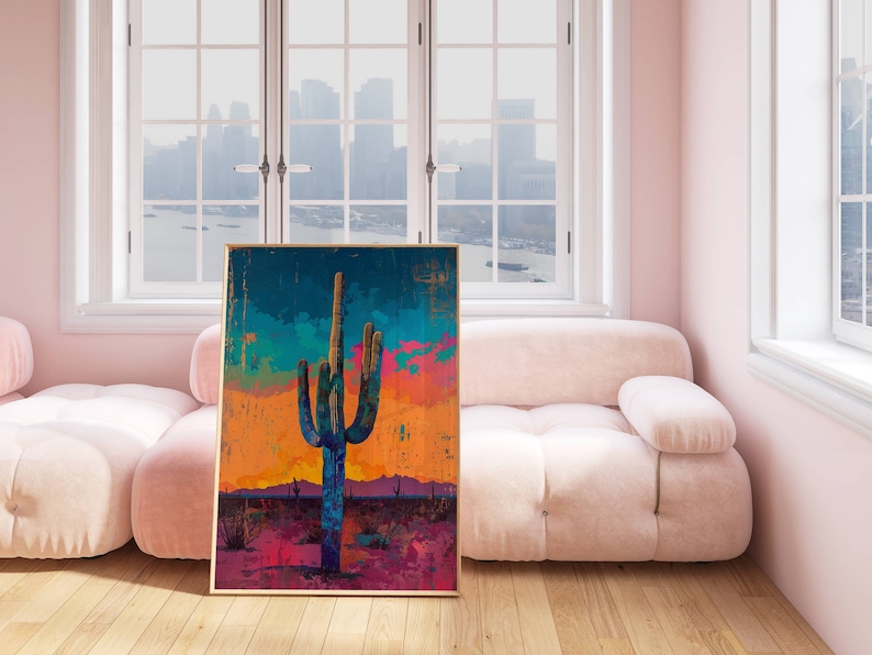 May include: A framed abstract painting of a large, blue cactus in a desert landscape with a colorful sunset in the background.
