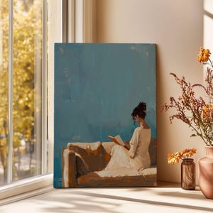 May include: An oil painting depicts a person reading on a sofa, set against a teal background. The artwork is displayed near a window with a view of fall foliage. A vase of dried flowers and a small glass jar with flowers are on a white surface.
