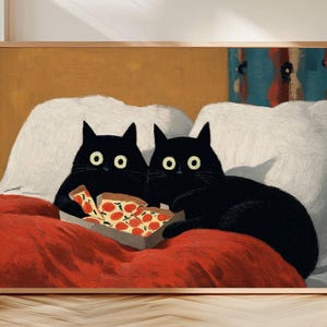 Puede incluir: Una impresión artística enmarcada que presenta dos gatos negros con ojos amarillos, descansando sobre una manta roja. Sostienen una caja de pizza con una pizza dentro. El fondo incluye almohadas blancas y una pared color canela.