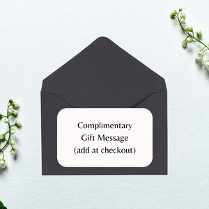 May include: A dark gray envelope with a white rectangle on the front that says "Complimentary Gift Message (add at checkout)"