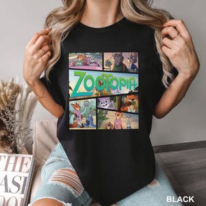 K&ouml;nnte beinhalten: Ein schwarzes T-Shirt mit einem Grafikdruck verschiedener Szenen aus dem Film Zoomania, einschlie&szlig;lich der Charaktere Nick Wilde und Judy Hopps. Das zentrale Design enth&auml;lt das Zoomania-Logo in gr&uuml;nem Text, angeordnet im Comic-Stil.