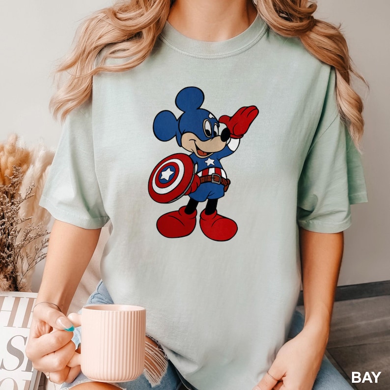 a woman holding a cup of coffee and wearing a mickey mouse t - shirt