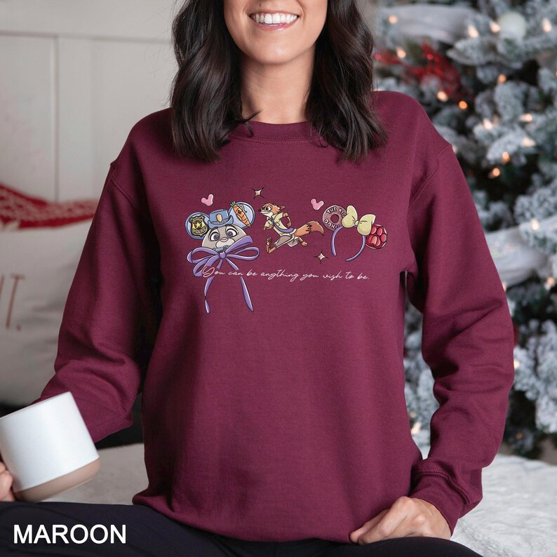 May include: Maroon sweatshirt featuring a cartoon design with the text "You can be anything you wish to be." The graphic includes a mouse in a police uniform, a fox, and mouse ears. The word "MAROON" is printed at the bottom of the image.