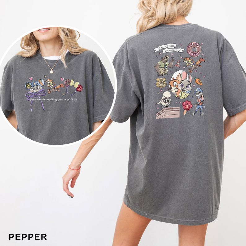May include: Pepper-coloured t-shirt with a colourful cartoon design. The front of the shirt has a design with the text "You can be anything you wish to be." The back of the shirt has a cartoon design with the text "The Big Donut."
