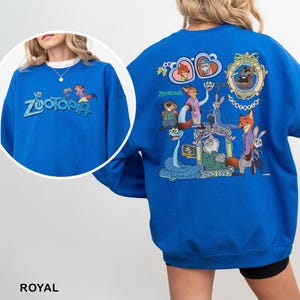 Puede incluir: Sudadera azul real de Zootopia con el logotipo de Zootopia y gr&aacute;ficos de personajes. La parte posterior presenta un gr&aacute;fico grande con m&uacute;ltiples personajes. La sudadera est&aacute; hecha de un material suave.