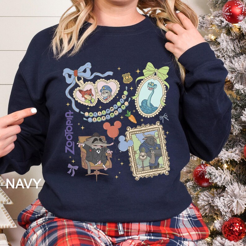 以下が含まれることがあります： ネイビーブルーのスウェットシャツ。ズートピアのキャラクターの額入りイラストが特徴です。デザインには、ニック・ワイルド、ジュディ・ホップス、その他のキャラクターが含まれています。「Zootopia」の文字がスウェットシャツの左側に縦にプリントされています。