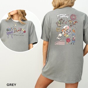 May include: Grey t-shirt with cartoon illustrations and text on the front and back. The front displays a mouse character with a bow and text. The back features multiple cartoon characters and the text "THE BIG DONUT".