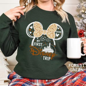 May include: A white ceramic mug with a black handle and the text "But First, Coffee" in a handwritten style. The mug is on a white surface. The mug is approximately 4 inches tall.